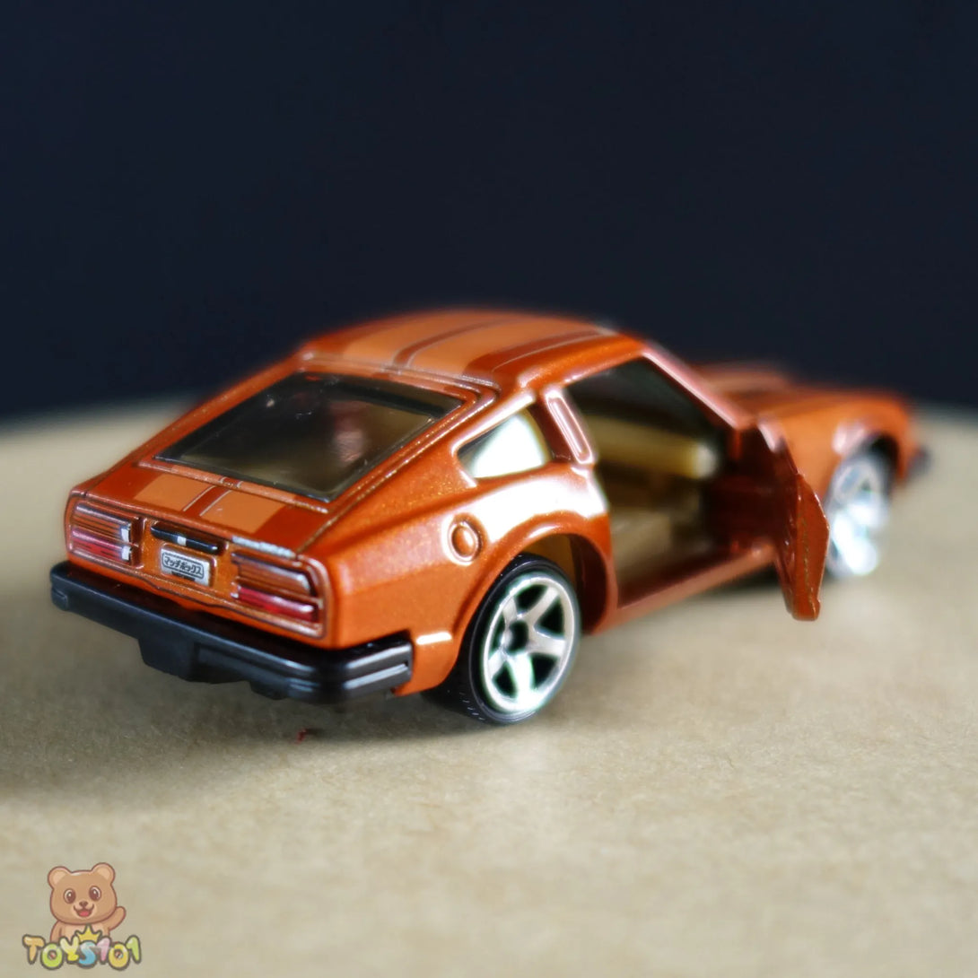 Orange 1:64 scale diecast Nissan 280ZX by Matchbox, viewed from the rear open passenger door.