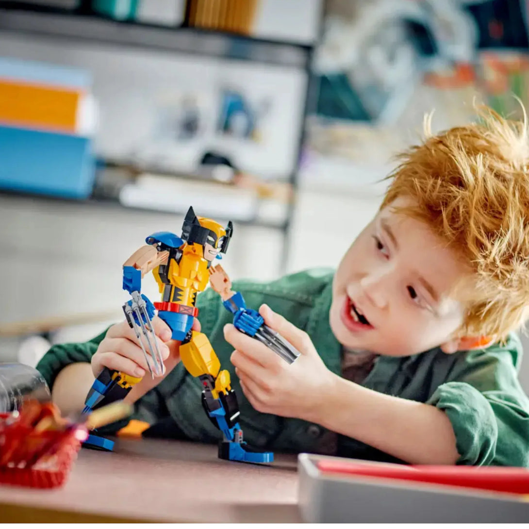Child playing with a LEGO Wolverine figure at a table.