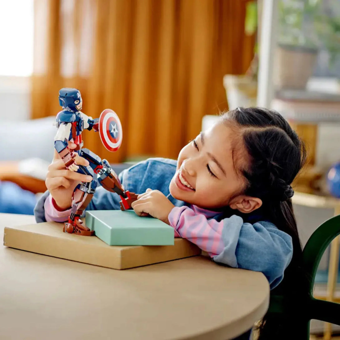 Child playing indoors with a LEGO 76258 Captain America superhero figure.