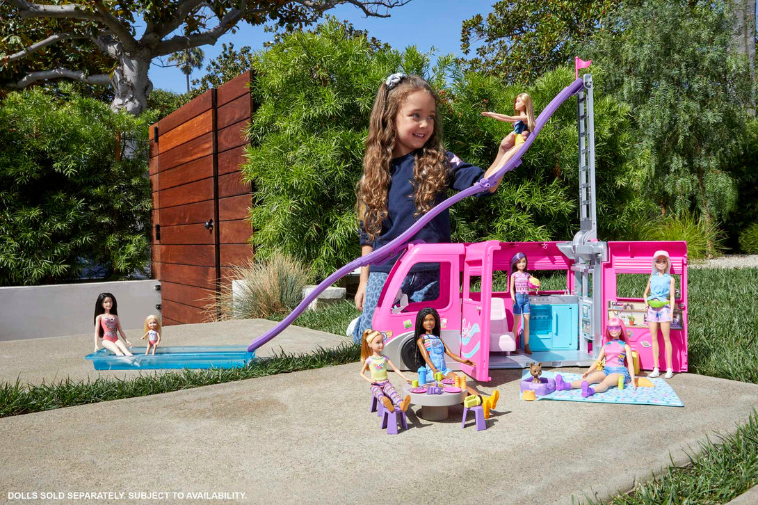 Child playing with a Barbie Dream Camper toy set outdoors